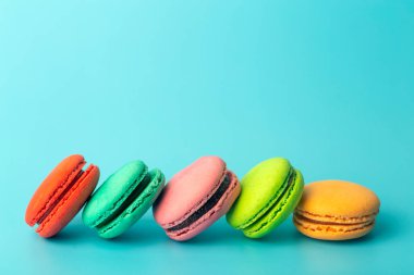 Mavi arka planda renkli kurabiyeler (badem kurabiyeleri). Parlak şenlikli hamur işleri, tatlılar ve tatlılar. Pişirme arkaplanı