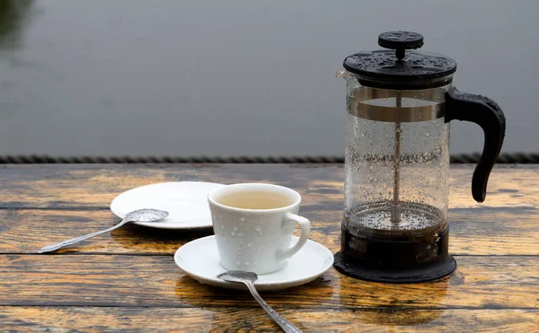 Sad, melancholy mood. Rain and coffee (tea) concept. Rain on the veranda of the summer cafe, a lonely cup of tea.