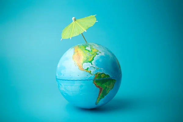 Global warming and climate change on earth concept. Earth globe on a blue background with an umbrella. Protecting the atmosphere from ultraviolet radiation and ozone holes