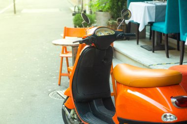 Roma 'da bir yaz caddesinde turuncu renkli scooter. İtalyan şehrinde bir yazlık kafe yakınlarında klasik scooter..