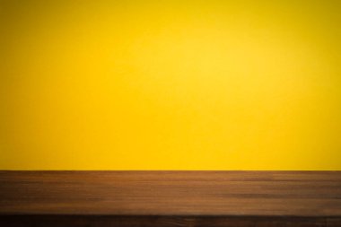 Ahşap masalı, boş, sarı bir sırt çantası. Boşluğu kopyala