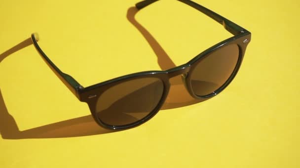 Sunglasses on a yellow background in the sunlight of the day. Summer, rest and relaxation concept. Minimal flat lay video — Stock Video