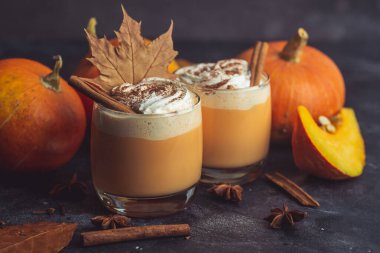 Balkabaklı latte içeceği. Baharatlı balkabağı aromalı sonbahar kahvesi ve koyu arkaplanda krema. Cadılar Bayramı ve Şükran Günü için Mevsimlik Sonbahar İçkileri