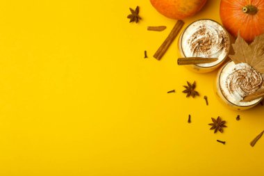 Balkabaklı latte içeceği. Baharatlı balkabağı aromalı sonbahar kahvesi ve sarı arka planda krema. Cadılar Bayramı ve Şükran Günü için Mevsimlik Sonbahar İçkileri