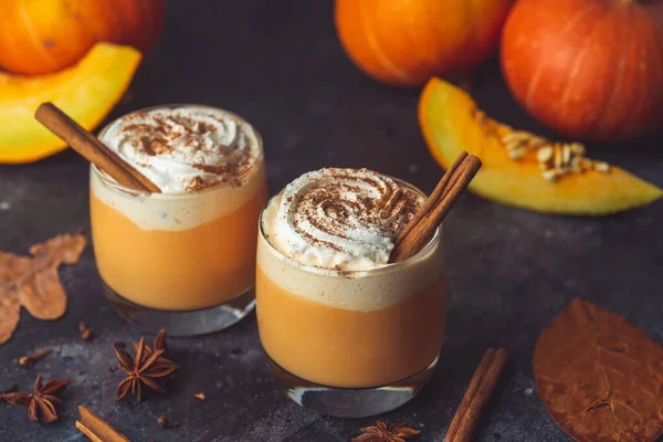 Pumpkin latte drink. Autumn coffee with spicy pumpkin flavor and cream on a dark background. Seasonal Fall Drinks for Halloween and Thanksgiving