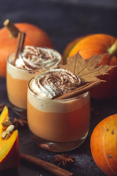 Pumpkin latte drink. Autumn coffee with spicy pumpkin flavor and cream on a dark background. Seasonal Fall Drinks for Halloween and Thanksgiving