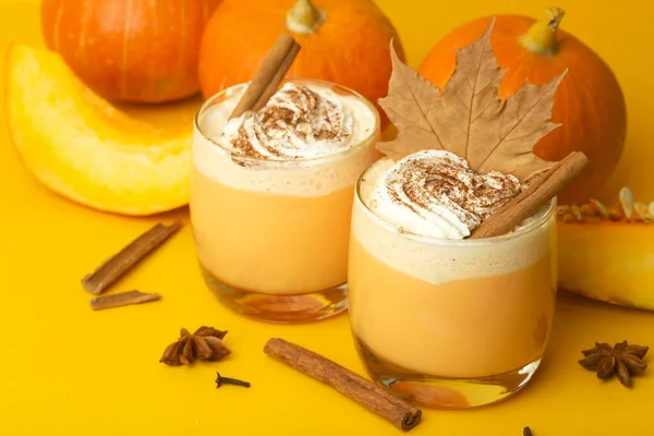 Pumpkin latte drink. Autumn coffee with spicy pumpkin flavor and cream on a yellow background. Seasonal Fall Drinks for Halloween and Thanksgiving