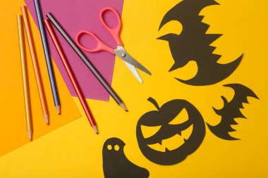 Cadılar Bayramı geçmişi. Sarı arka planda kağıttan kesilmiş siyah yarasalar. Renkli kağıttan Cadılar Bayramı ev dekorasyonu yapmak.