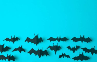 Cadılar Bayramı geçmişi. Mavi arka planda kağıttan kesilmiş siyah yarasalar. Bayram için Cadılar Bayramı dekorasyonu ve süslemeleri, kopya alanı.