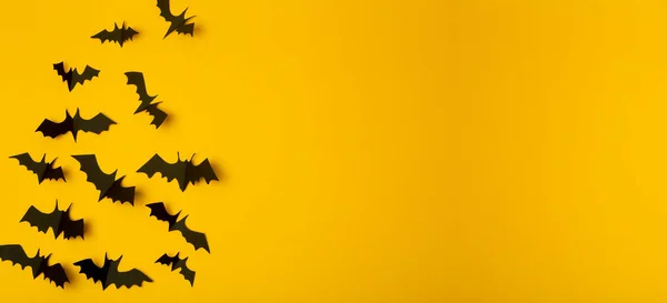 Halloween banner background. Black bats cut from paper on a yellow background. Halloween decor and decorations for the holiday, copy space.