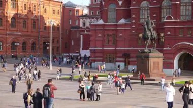 Moskova 'da Kremlin yakınlarındaki Manezhnaya Meydanı' nda. Moskova 'da turistler güneşli havada Kremlin yakınlarındaki şehir merkezinde yürürler..