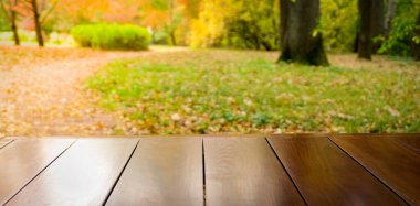 Sonbahar masa arkaplanı. Güneşli bir günde bir sonbahar parkının arka planındaki tahta masa. Ürün ve nesne için yer
