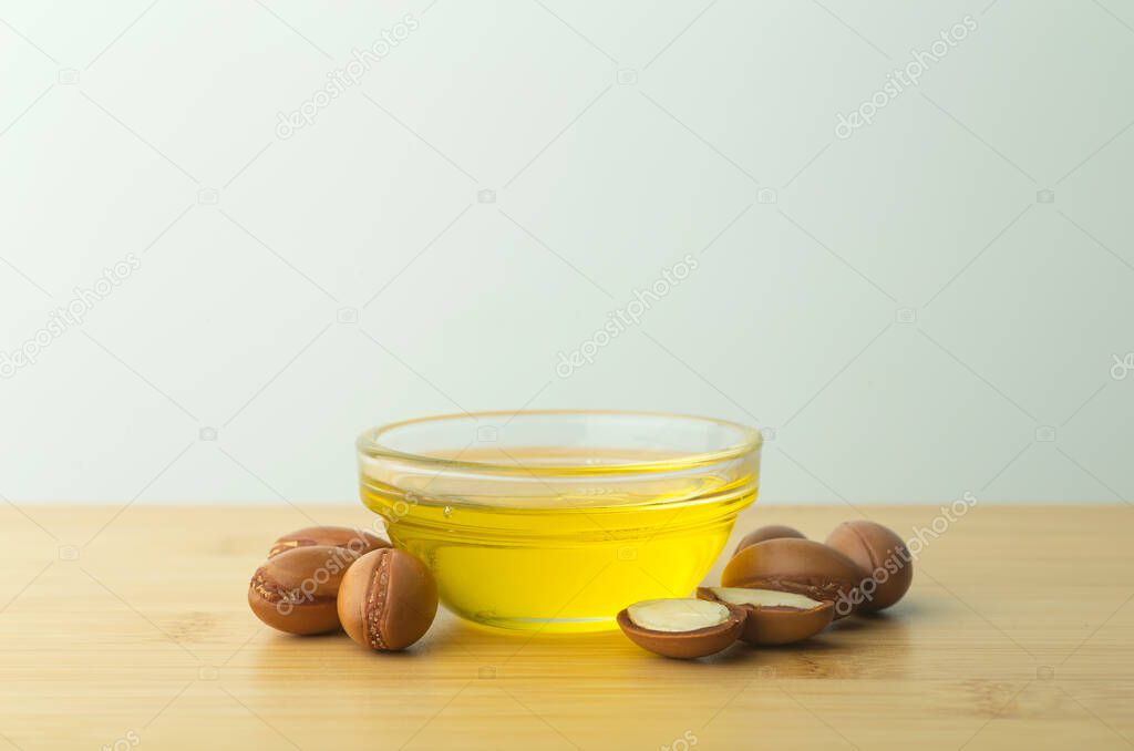 Argan oil background. Argan nuts  and oil on a wooden table on a empty white background. Copy space