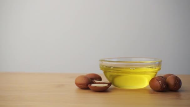 Beyaz arka planda argan tohumları olan cam bir kâseye Argan yağı. Argan yağı bazlı kozmetik konsepti. — Stok video