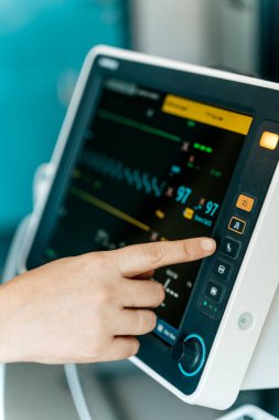 Hastane ortamında ekranda hayati belirtileri olan modern bir tıbbi hasta monitöründe bir tuşa basıyorum..