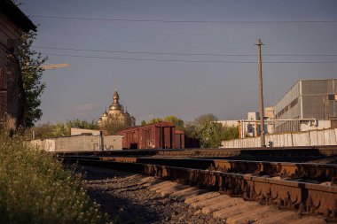 Düşen gölgesi olan bir demiryolu. Yaz. Bahar. Akşam. Mavi gökyüzü Gün batımı. Şehir manzarası. Şehrin varoşları.