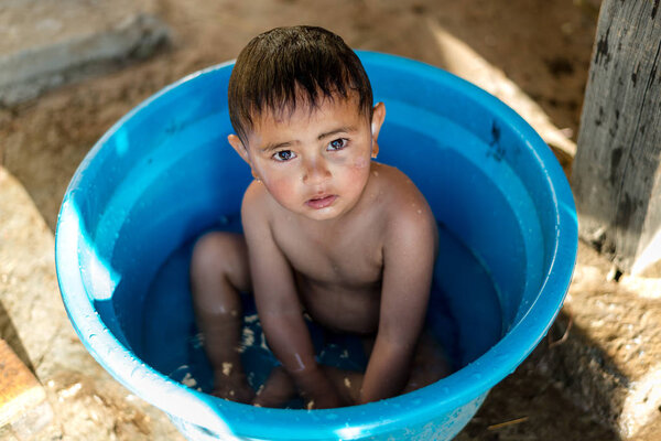 Kullu, Himachal Pradesh, India - March 01, 2019 : Photo of Himalayan kid taking bath in tub in Himalaya, Sainj Valley