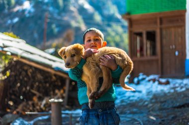 Kullu, Himachal Pradesh, Hindistan - 26 Ocak 2019 : Dağlarda köpekle oynayan mutlu çocuk