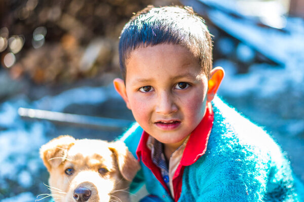 Kullu, Himachal Pradesh, India - January 26, 2019 : Happy boy playing with dog in mountains