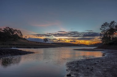 Yalnız ağaç üzerinde gündoğumu gölde