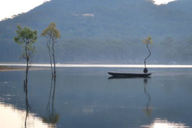 göl ve kayıkçı bahar güneş doğarken yansıtan yeşil taze yaprakları ile batık ağaçlar