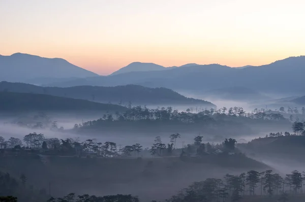 雾覆盖了脚下山的小村庄与黎明时的神奇的光 — 图库照片