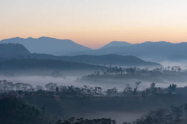 雾覆盖了脚下山的小村庄与黎明时的神奇的光 — 图库照片