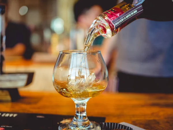 Bir şişe burbon fotoğrafını kapalı sıçrama ve buz ile görünümü kadar yakın bir yudum içine dökme