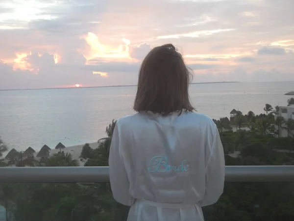 Sırtından düşen kadın bulutlu gün batımını izliyor