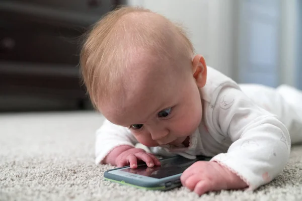 Meraklı küçük bebek bir cep odaklanmak için çalışıyor