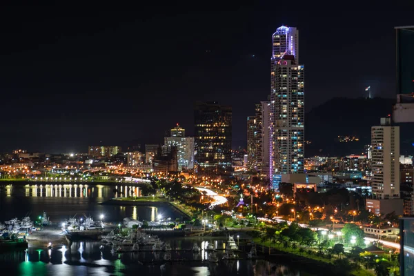 ] Νυχτερινή θέα της πόλης του Παναμά, Παναμάς με τα πολύχρωμα φώτα κατά μήκος της προκυμαίας αντανακλάται στο νερό και τους σύγχρονους ουρανοξύστες στον ορίζοντα — Φωτογραφία Αρχείου