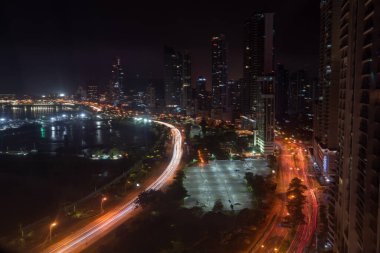Panama 'nın Panama şehrinin gece manzarası. Rıhtım boyunca renkli ışıklar suya ve gökdelenlere yansıyor.