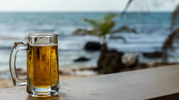 Yaz tatilinde deniz manzaralı cam bardakta soğuk bir bira.