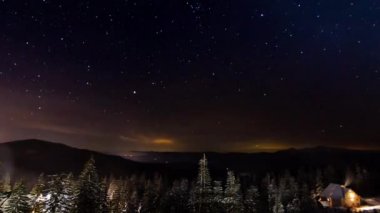 Yıldız Timelapse: yıldızlar kışın dağlarda küçük ev üzerinde hareketli. Ural Dağları 'Nda çam ormanında küçük barınak, Rusya.