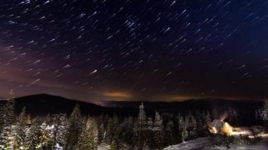 Yıldız Timelapse: Kışın dağlarda küçük evin üzerinde hareket eden yıldızlar. Ukrayna, Karpat
