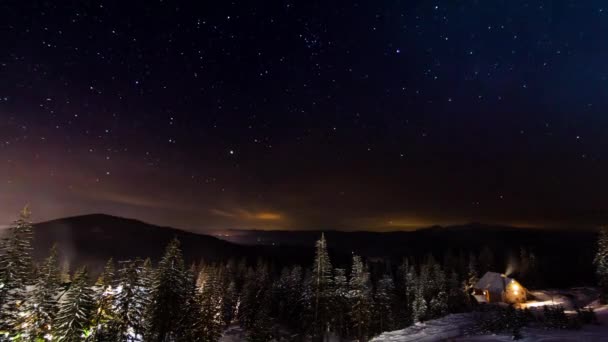 Estrellas moviéndose por encima de la pequeña casa en las montañas en WInter. Ucrania, Cárpatos — Vídeos de Stock