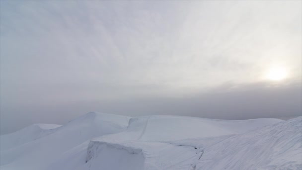 높은 바위 산과 눈 덮인 계곡의 놀라운 흰색 풍경을 통해 푸른 하늘에 실행 구름의 시간 경과 — 비디오