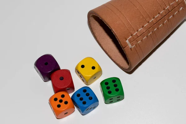 colorful cubes in front of a part of a leather cube mug in front view photographed in close up and macro as a cut out