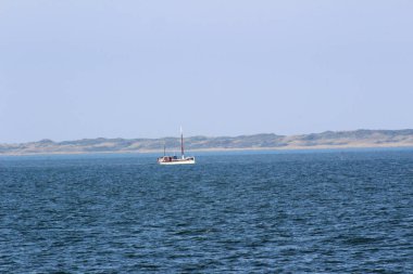 Kuzey Deniz Adası Juist Almanya üzerinde mavi bir gökyüzü altında ufukta su ve tekneler hareketli uzak görünüm güneşli bir günde bir gezi turu fotoğraflandı