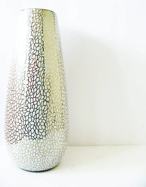 Tall white vase with lines crossing through the entire surface with a white background