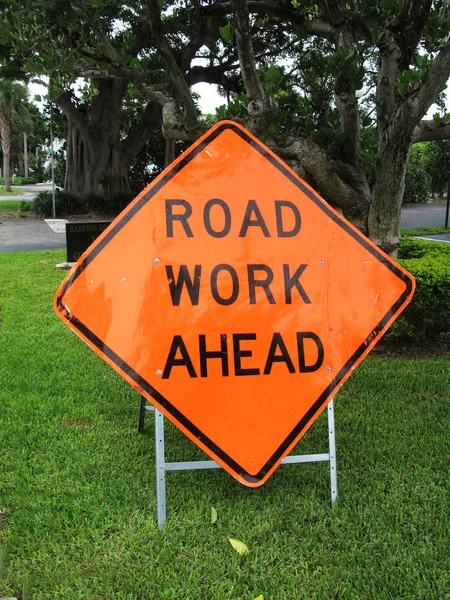 Road Work Ahead Metal Traffic Orange Sign on a street lawn