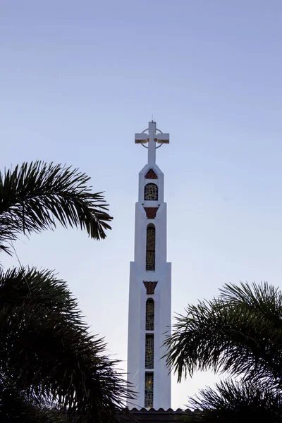 Community Catholic Church White Concrete Cross with a blue sky background. Church Cross with Palm Trees and Blue Sky.