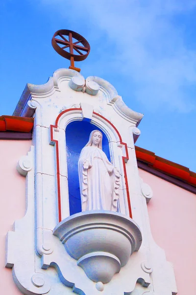 Community Catholic Church with a White Stone Female Religious Figure on top of the entrance of the Chapel.