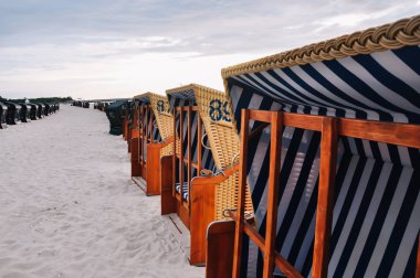 Plaj sandalyeleri bir satırda döken kulübesinde mavi beyaz desen çıkardı. Tatil deniz tarafından.