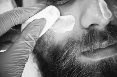 Yetişkin erkekte güzellik stüdyosu, Şevval özçelik güzellik kaldırma yüz maskesi veya nemlendirici krem sakallı. Siyah beyaza yakın atış.