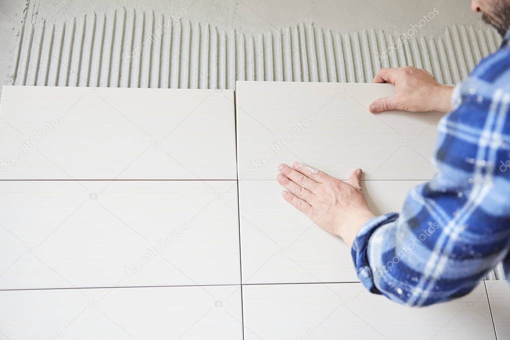 Worker laying tile in new home