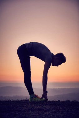 Güneş ışığı, uçurumdaki germe egzersiz yapan erkek