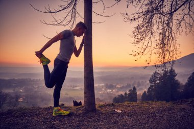 Güneş ışığı, uçurumdaki germe egzersiz yapan erkek