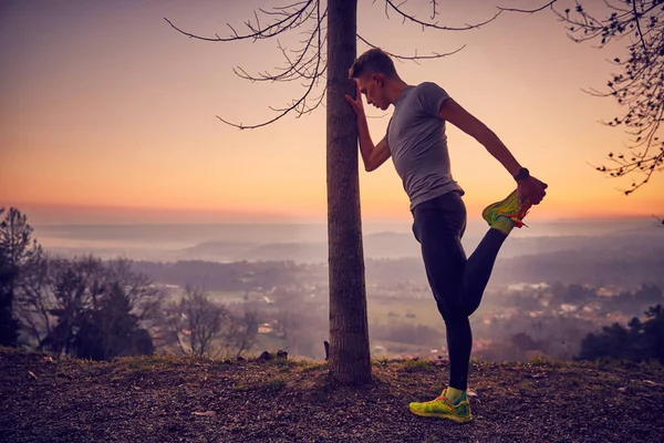 Güneş ışığı, uçurumdaki germe egzersiz yapan erkek