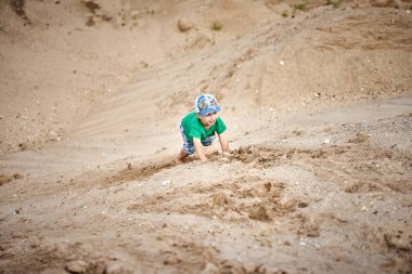 bir çocuk bir kum tepe tırmanıyor
